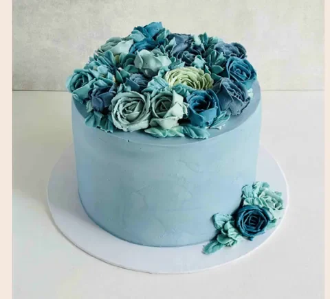 A cake with blue roses piped in buttercream